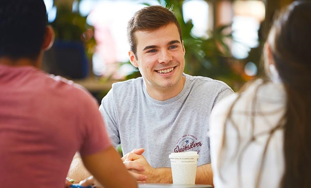 Murdoch student sitting with friends drinking coffee