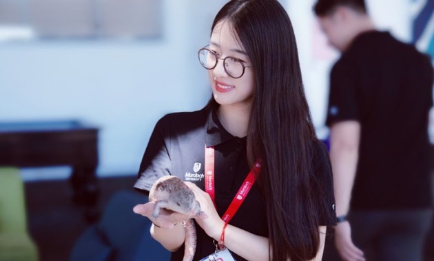 Murdoch student smiles while holding lizard