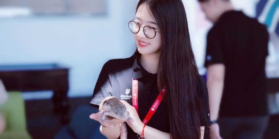 Murdoch student smiles while holding lizard