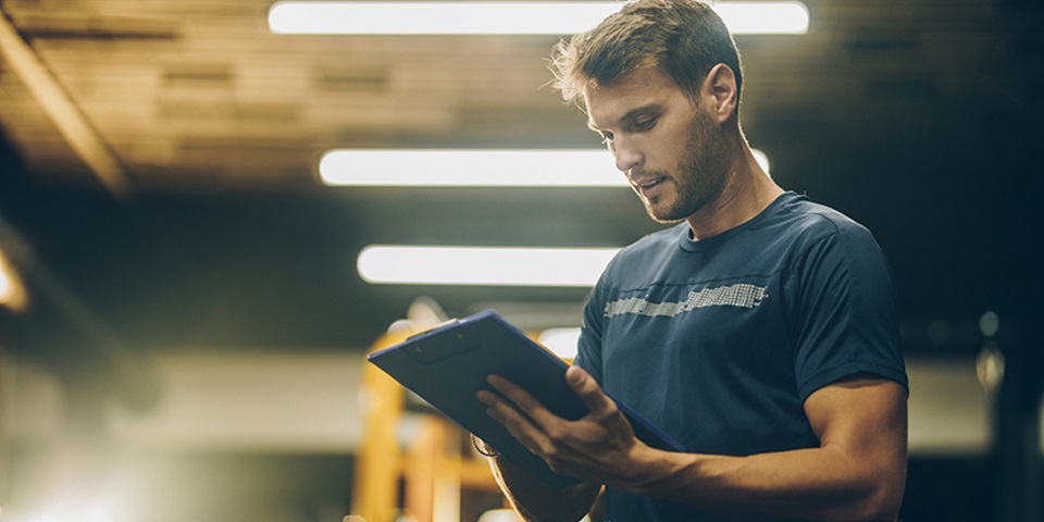 Strength and conditioning coach assessing training in the gym