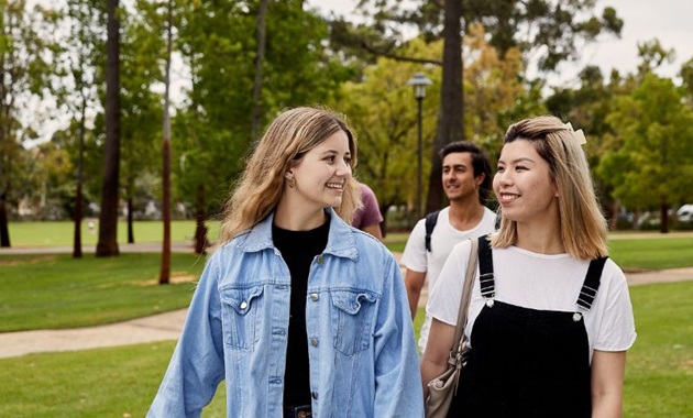 Two students walking on campus smiling at each other