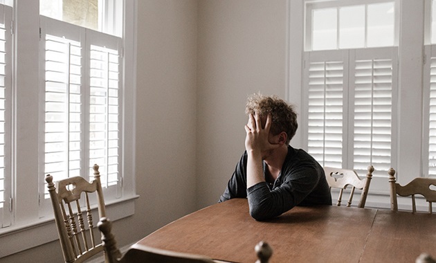 Teenage boy sitting with head in head at table