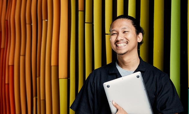 Murdoch student smiling off camera holding a laptop.