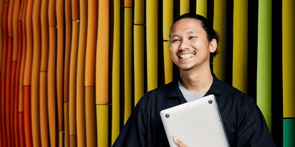 Murdoch student smiling off camera holding a laptop.